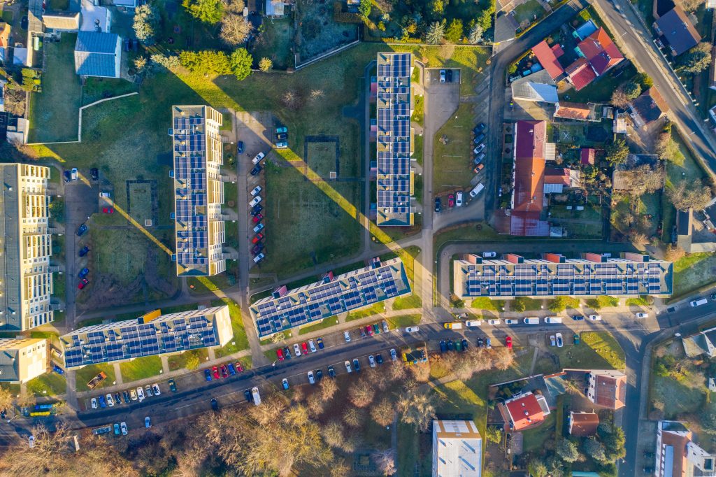 Vue aérienne de bâtiments équipés de panneaux photovoltaïques en toiture pour produire de l’énergie solaire locale.