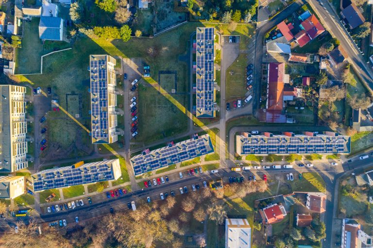 Vue aérienne de bâtiments équipés de panneaux photovoltaïques en toiture pour produire de l’énergie solaire locale.