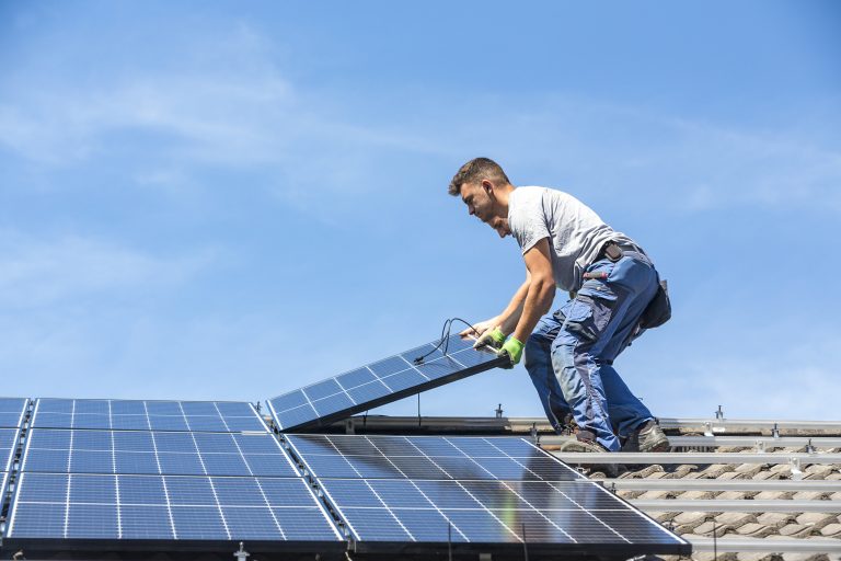 Installing solar photovoltaic panel system. Solar panel technician installing solar panels on roof. Alternative energy ecological concept